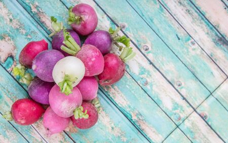 Pink, dark red, red, and purple radish over wooden backgroundの写真素材