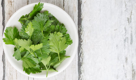 Fresh parsley leaves in white bowl over wooden background