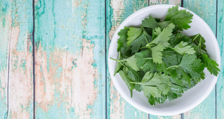 Fresh parsley leaves in white bowl over wooden background