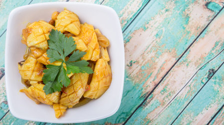 Malaysian dish stir fried squid with parsley leaves in white bowl over wooden background