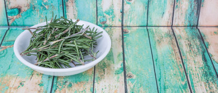 Fresh rosemary herbs over in white bowl over wooden backgroundの写真素材