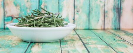 Fresh rosemary herbs over in white bowl over wooden backgroundの写真素材