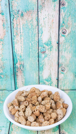 Dried white mulberry in white bowl over wooden backgroundの写真素材