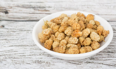 Dried white mulberry in white bowl over wooden backgroundの写真素材