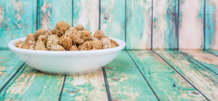 Dried white mulberry in white bowl over wooden backgroundの写真素材