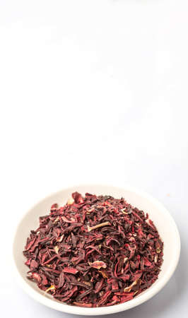 Dried red hibiscus tea leaves in white bowl over white backgroundの写真素材