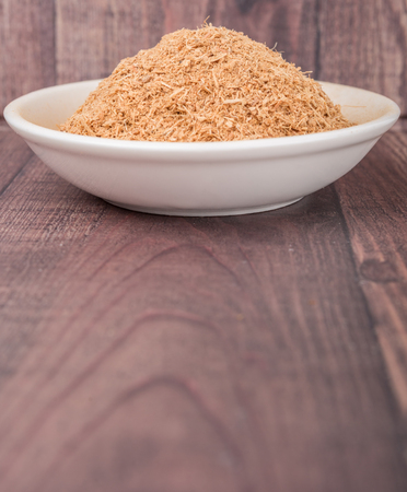 Dried galangal powder in white bowl over wooden backgroundの写真素材