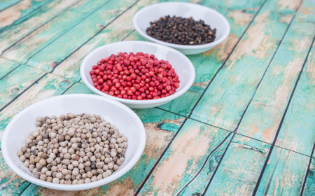 Black, pink and white peppercorn over wooden backgroundの写真素材