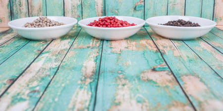 Black, pink and white peppercorn over wooden backgroundの写真素材