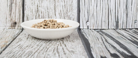 White peppercorn in white bowl over wooden background
