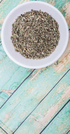Dried lemon balm leaves in white bowl over white backgroundの写真素材