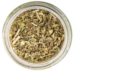 Dried lemon balm leaves in a mason jar over white backgroundの写真素材