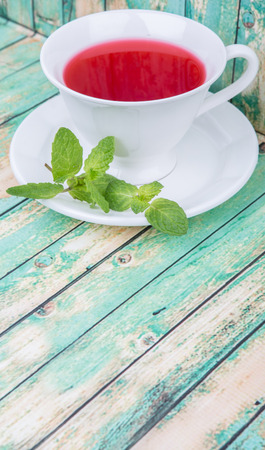 A cup of hibiscus tea with fresh mint leaves over wooden backgroundの写真素材