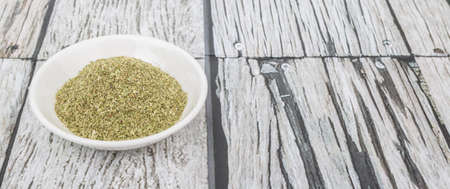Dried oregano herbs in white bowl over wooden backgroundの写真素材