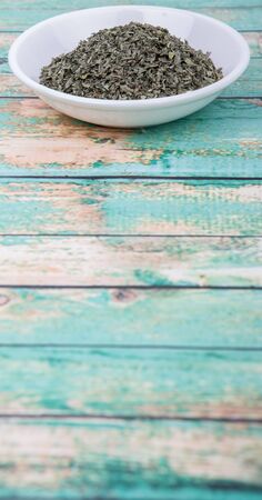 Dried basil leaves herbs over in white bowl over wooden backgroundの写真素材