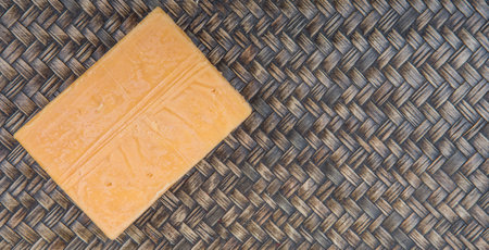 A block of cheddar cheese over wicker backgroundの写真素材