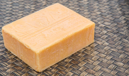 A block of cheddar cheese over wicker background