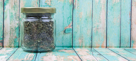 Dried Japanese green tea leaves in a mason jar over wooden backgroundの写真素材