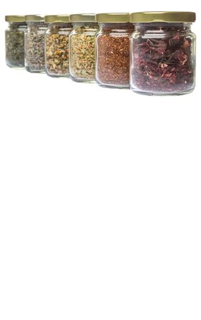 Dried herbal tea lavender, chamomile, linden flower, rooibos, hibiscus, Japanese green tea in mason jars over white backgroundの写真素材