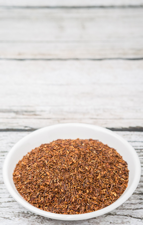 Dried rooibos herbal tea in white bowl over wooden backgroundの写真素材
