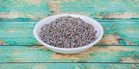 Dried lavender herbal tea in white bowl over wooden backgroundの写真素材