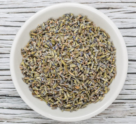 Dried lavender herbal tea in white bowl over wooden backgroundの写真素材