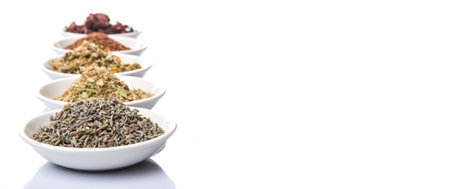 Dried herbal tea leaves, lavender, rooibos, chamomile, linden flower, hibiscus, Japanese green tea in white bowl over white backgroundの写真素材