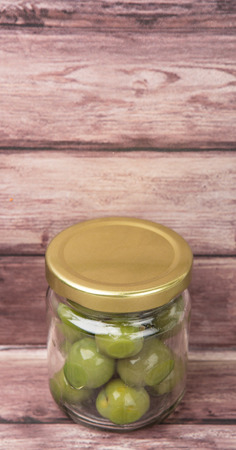 Pickled olive fruit in mason jar over wooden backgroundの写真素材