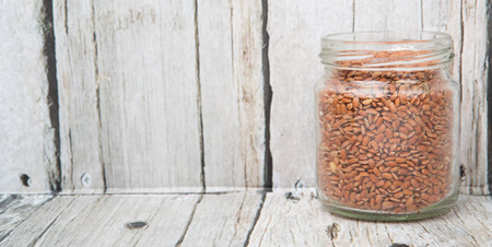 Brown millet grain seed in a mason jar over wooden backgroundの写真素材