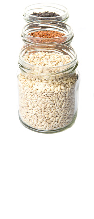 White, brown, black millet in mason jars over white backgroundの写真素材