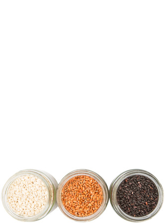 White, brown, black millet in mason jars over white backgroundの写真素材
