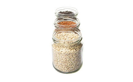White, brown, black millet in mason jars over white backgroundの写真素材