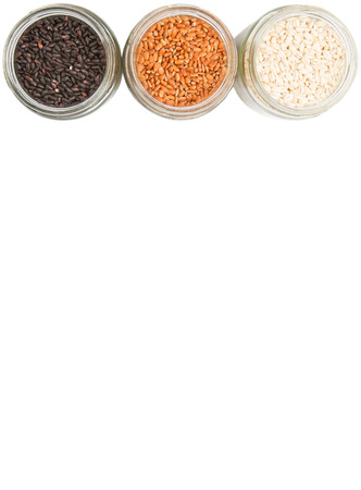 White, brown, black millet in mason jars over white backgroundの写真素材