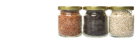 White, brown, black millet in mason jars over white backgroundの写真素材