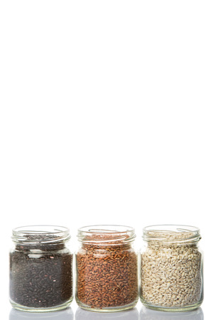 White, brown, black millet in mason jars over white backgroundの写真素材