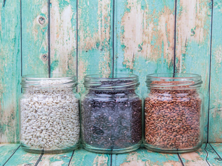 White, brown, black millet in mason jars over wooden backgroundの写真素材