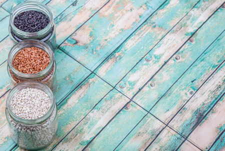 White, brown, black millet in mason jars over wooden backgroundの写真素材