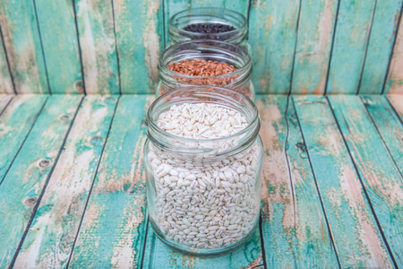 White, brown, black millet in mason jars over wooden backgroundの写真素材