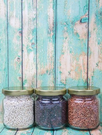 White, brown, black millet in mason jars over wooden backgroundの写真素材