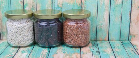 White, brown, black millet in mason jars over wooden backgroundの写真素材