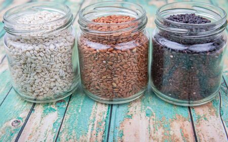 White, brown, black millet in mason jars over wooden backgroundの写真素材