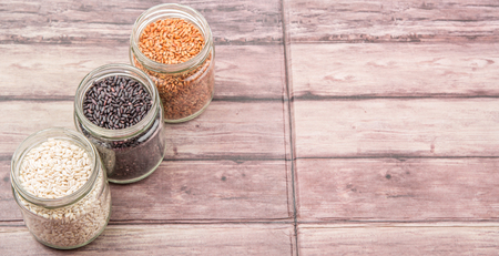 White, brown, black millet in mason jars over wooden backgroundの写真素材