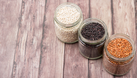 White, brown, black millet in mason jars over wooden backgroundの写真素材