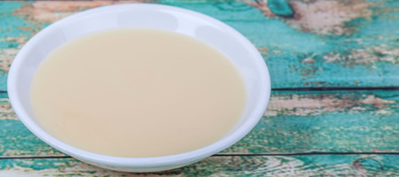 Sweet condensed milk in white bowl over wooden backgroundの写真素材