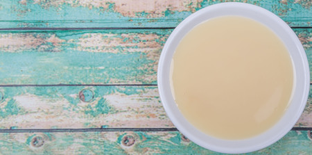 Sweet condensed milk in white bowl over wooden backgroundの写真素材