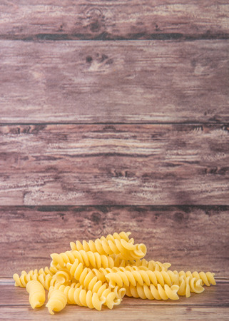 Dried corkscrew shape pasta or rotini pasta over wooden backgroundの写真素材