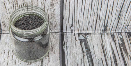 Black sesame seed in mason jar over wooden background