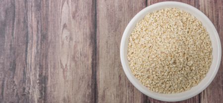White sesame seed in white bowl over wooden backgroundの写真素材