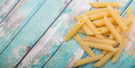 Dried penne regate pasta over wooden backgroundの写真素材