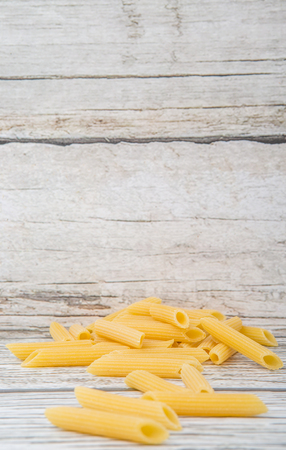 Dried penne regate pasta over wooden backgroundの写真素材